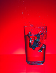 ice cubes falling into glass of water