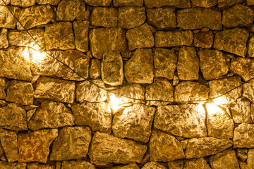 yellow golden lamp bulbs on a old vintage stone wall background in loft or vintage style , concept...