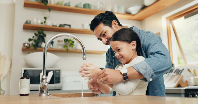 Girl Washing Her Hands With Her Father In The Kitchen For Hygiene, Health And Wellness At Home. Child Learning To Clean Her Skin With Young Dad With Soap And Water To Prevent Germs, Dirt Or Bacteria.