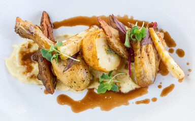 Close up of roast chicken with potatoes, parsnips and gravy on white plate in restaurant