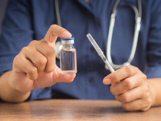 Doctor holding a syringe and vial with medication for injection.