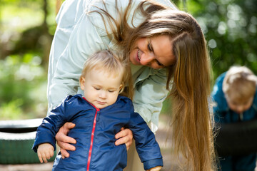 The mother with two children is having a fun time at the playground.