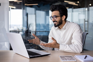 Online meeting, conference. Indian young man, office worker and businessman prays on laptop for...