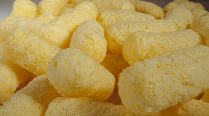 Close up of yellow air corn sticks close-up. Crunchy corn snacks texture. Selective focus