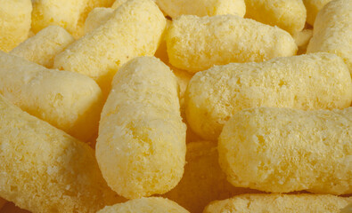 Close up of yellow air corn sticks close-up. Crunchy corn snacks texture. Selective focus