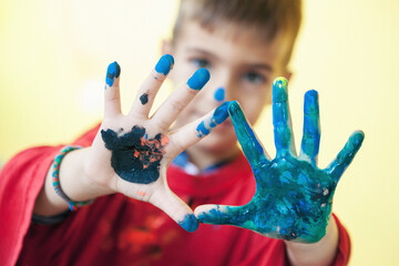 Boy painting with hands using water colors