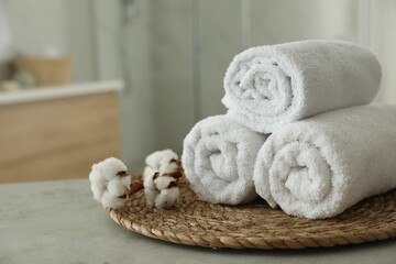 Fototapeta na wymiar Clean rolled towels and cotton flowers on table in bathroom. Space for text