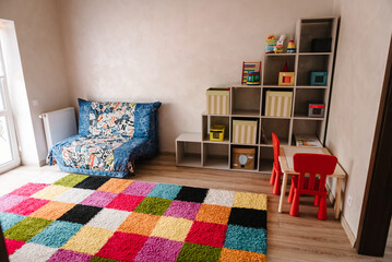 Stylish interior of the modern playroom in kindergarten. Game room in of new premises. Spacious bright game room in the kindergarten with toys, large windows and table for classes. Natural light.