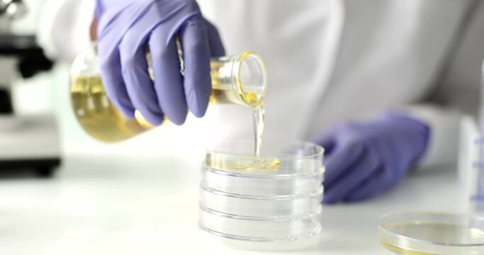 Hand pours yellow liquid into test tube closeup. Examination of petroleum products and fuels and lubricants
