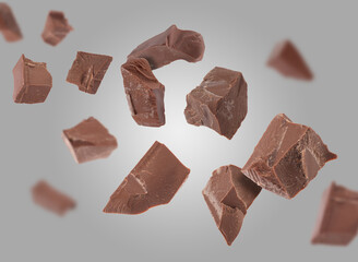 Tasty chocolate chunks falling on grey background