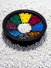 various colors of masterbatch granules in a round palette, isolated on a white background. This...