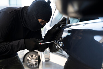 A young man who is breaking into a car.