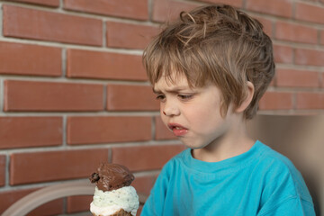 Boy grimacing to look at the ice cream. He doesn't like it