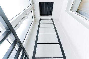 A ladder made of composite material going up against the parallel facade of a building with...