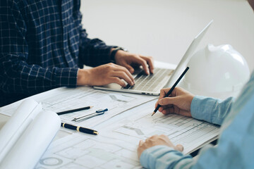 Architectural engineer team drawing on blueprint and meeting for project working with a partner on...