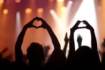 Music lovers. Heart hands, love and silhouette at music festival, kindness and peace emoji or symbol at concert. People, audience and back of crowd at party or event,.