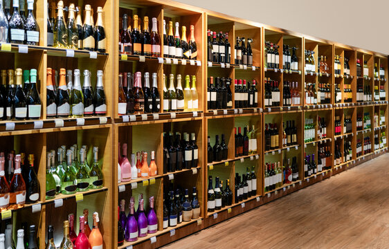 Big retail shelves with different wine bottles and selective focus. Banner for liquor store and wine production industry.