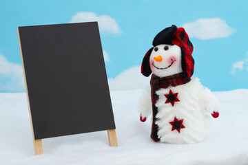 Snowman with hat and scarf and blank chalkboard with snow