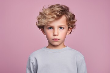 Portrait of a cute little boy with blond curly hair. Isolated on pink background.