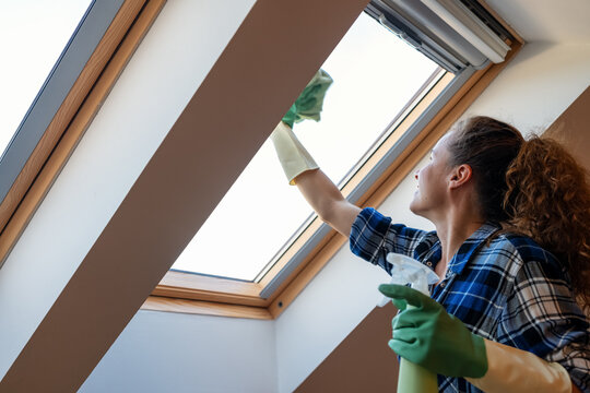 Woman washes skylight window at home. Housework, keeping house clean and tidy.