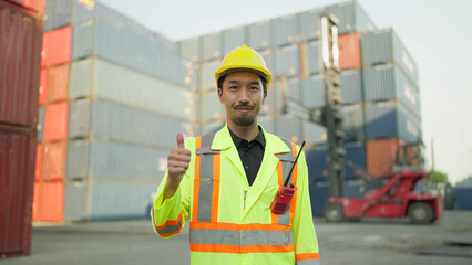 Portrait young asian japanese foreman in hardhat and safety uniform standing giving thumbs up while smiling at the camera. Engineer giving thumbs up while looking at camera. Logistic concept