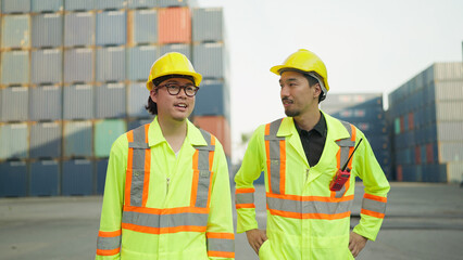 Young industrial engineer walking with foreman worker inspecting cargo boxes at container yard warehouse shipping port and shaking hands for sucess working. Cargo shipping, Teamwork concept