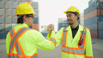 Two asian engineer or foreman shaking hand after working checking at container cargo harbor to...