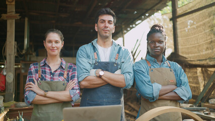 Portrait of three confident carpenters man and woman standing with arms crossed looking at camera....