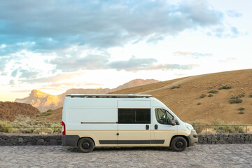 Obraz premium A white van is parked on the side of a road amidst natural surroundings.
