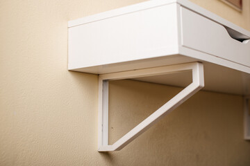A compact white floating desk with a geometric support bracket for small spaces.