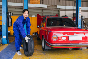 Asian Japanese male mechanic worker portrait in auto service workshop car tyre maintenance center...