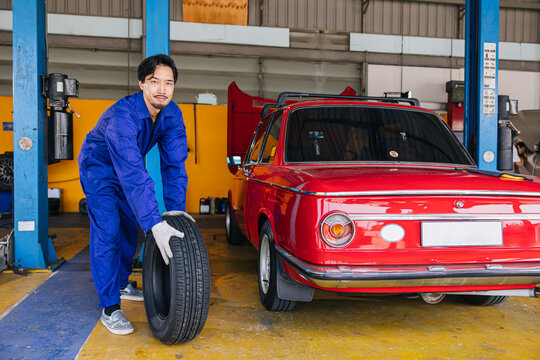 Asian Japanese male mechanic worker portrait in auto service workshop car tyre maintenance center replace fix auto part
