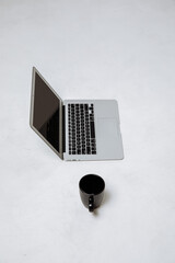 Black cup with coffee and laptop