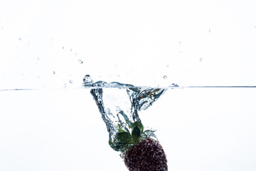 Fresh strawberry plunging into water, creating a captivating splash. Perfect for beverage advertisements or refreshing summer-themed content. 