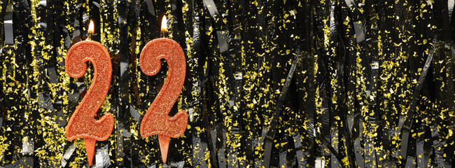 Burning red birthday candles on glitter tinsel background, number 22. Banner.