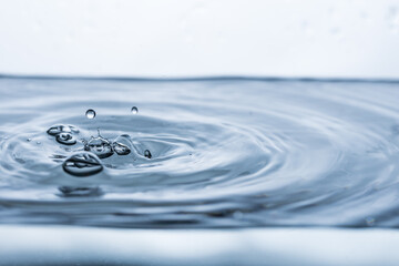 Captivating image of a water droplet reflecting on a pristine white surface, surrounded by...