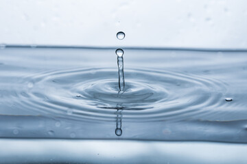 A mesmerizing water droplet reflecting on a pristine white surface, creating a captivating splash.