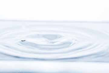 A tiny whirlpool on the water's surface amidst gentle waves against a pristine white backdrop....