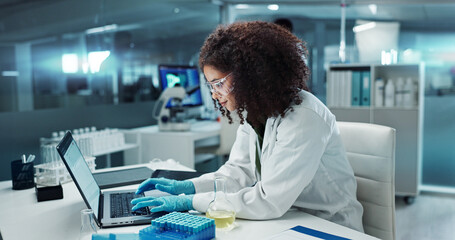 Scientist, woman and typing on laptop with test tube for chemistry, research or experiment at lab....