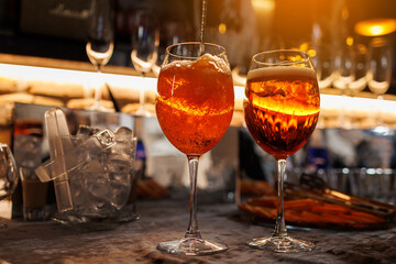 Two glasses of cocktail Aperol spritz on bar counter. Making typical alcoholic italian beverage,...