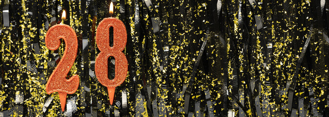 Burning red birthday candles on glitter tinsel background, number 28. Banner.