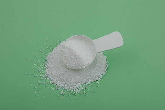 Pile of Sodium percarbonate powder SPC or sodium carbonate peroxide in measuring spoon. White granulated powder with formula Na2H3CO6 used in eco-friendly bleaches and other cleaning products