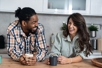 Simple living. Young couple drinking their first morning coffee in the kitchen discussing improving...