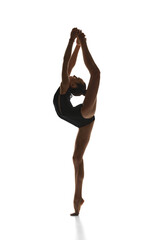 Full-length image of teen girl rhythmic gymnast in stage costume performing against white studio background. Flexibility. Concept of sport, beauty and grace, competition, art, youth, hobby