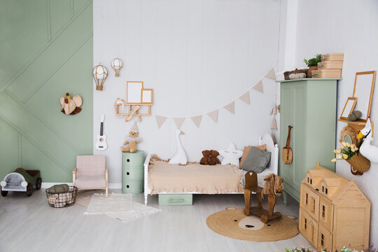 Stylish baby room with toys, wooden bed and mock up poster frame. Cute home decor. Scandinavian interior of a children's room.