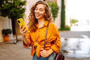 Young woman walking down the street and using mobile phone. Business, technology, blogging,...
