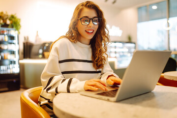 Young woman sitting on cafe with laptop. Beautiful college student on a cafe. Concept for...