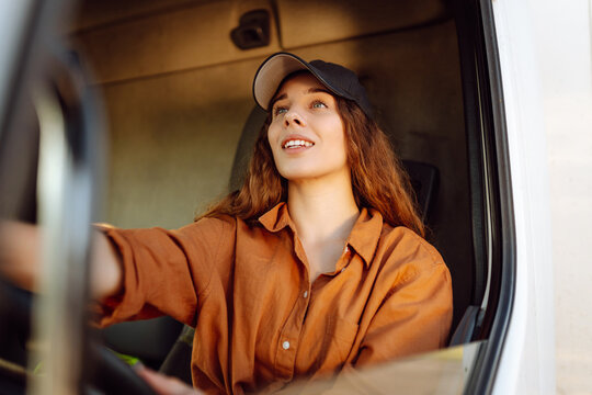 Female driver looking out of truck window. Transport industry theme