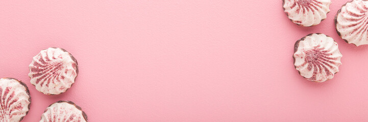 Beautiful white vanilla soft zephyrs with dry strawberry powder on light pink table background....