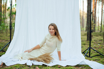 a woman in a white evening dress with sequins on a white background in the forest. dry yellow grass...